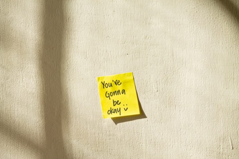 Sticky note on wall reading “You’re gonna be okay” — part of a remote work setup for chronic pain.