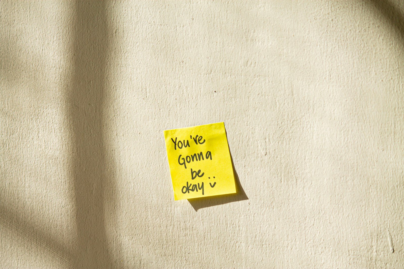 Sticky note on wall reading “You’re gonna be okay” — part of a remote work setup for chronic pain.