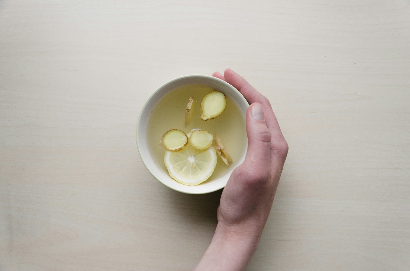 Hand holding a warm mug of lemon water — a ritual of calm in chronic pain