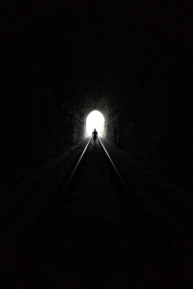 Figure walking toward light at end of a dark tunnel — symbolizing resilience and hope through chronic pain