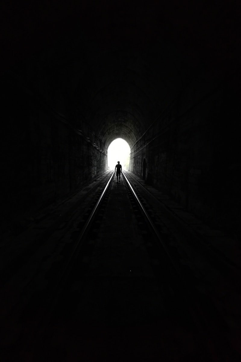 Figure walking toward light at end of a dark tunnel — symbolizing resilience and hope through chronic pain