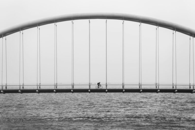 Silhouette of a person cycling across a bridge, symbolizing how boundaries create connection while living with chronic pain.